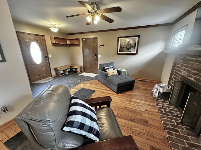 living area featuring a fireplace, crown molding, baseboards, and hardwood / wood-style flooring