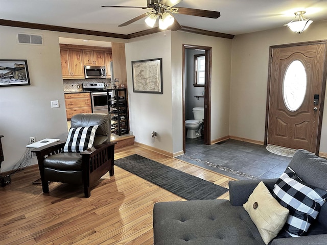 living room with light wood-type flooring, visible vents, plenty of natural light, and baseboards