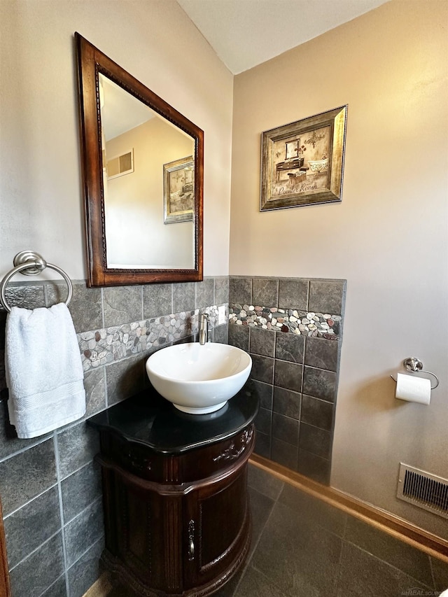 bathroom with visible vents, tile walls, vanity, and a wainscoted wall