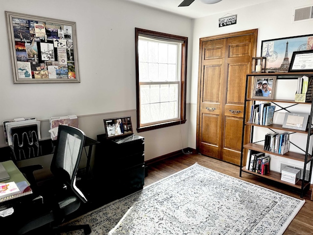 office space featuring a ceiling fan, wood finished floors, visible vents, and baseboards