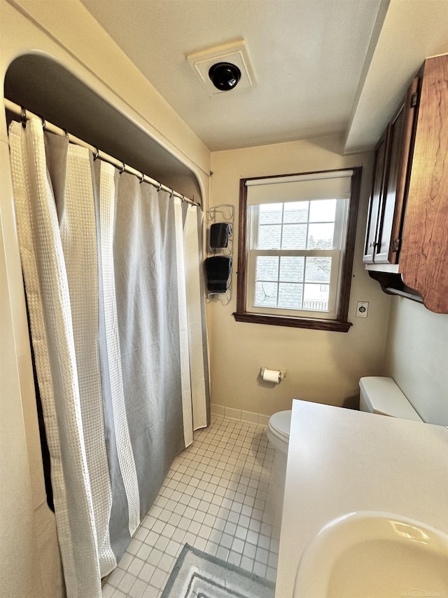 full bath with baseboards, toilet, a shower with shower curtain, tile patterned floors, and a sink