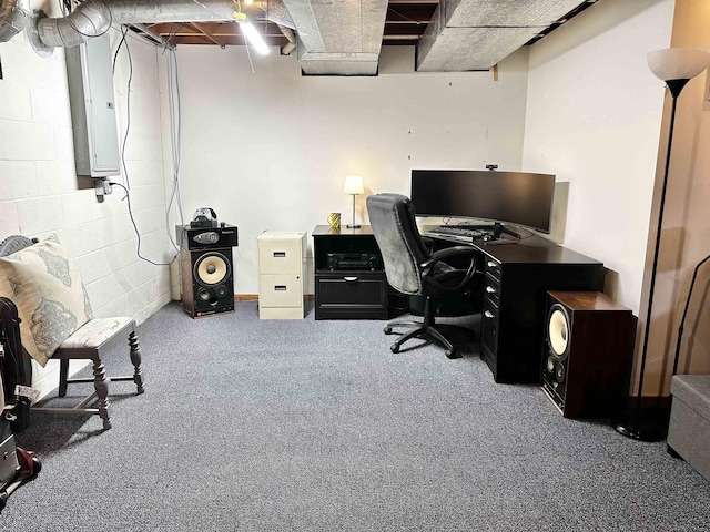 office area featuring electric panel, concrete block wall, and carpet