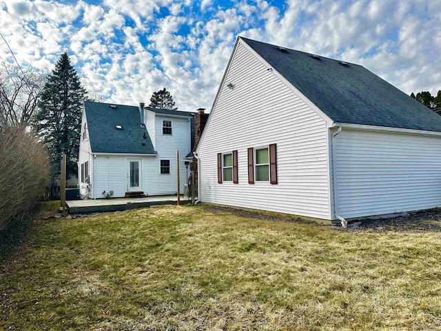 rear view of property featuring a patio area, a yard, and roof with shingles