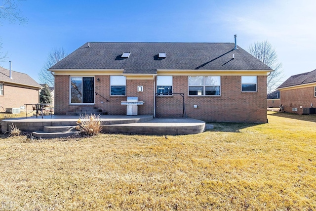 rear view of house featuring a yard, brick siding, and a patio area