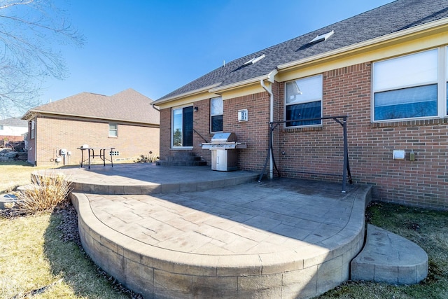 back of house with a patio, brick siding, and roof with shingles