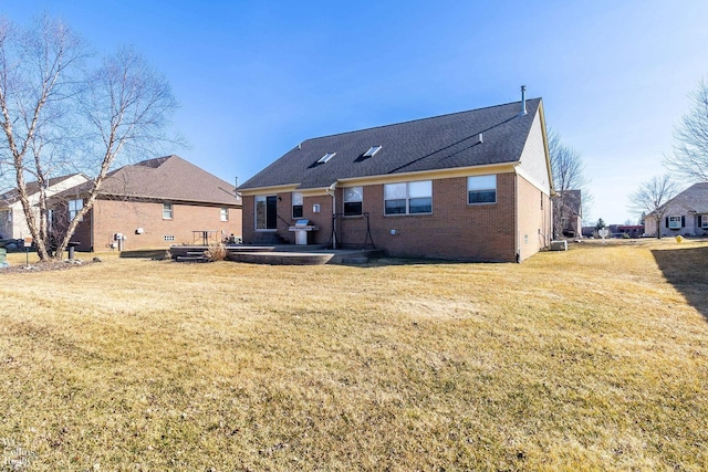 back of property featuring brick siding and a yard