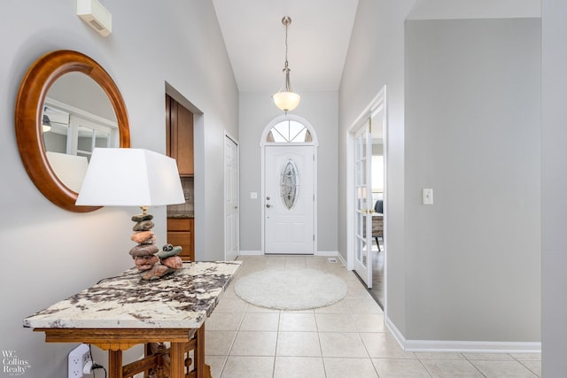 entryway with light tile patterned floors, baseboards, and vaulted ceiling