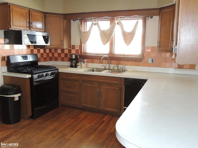 kitchen featuring brown cabinets, a sink, dark wood-style floors, appliances with stainless steel finishes, and light countertops