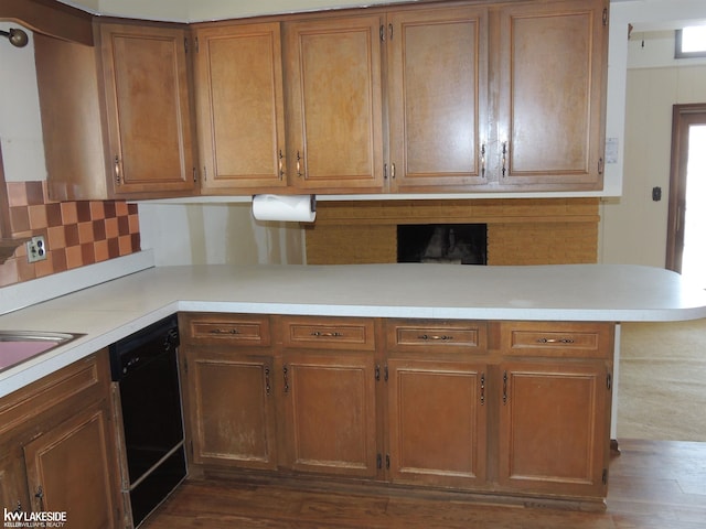 kitchen with backsplash, light countertops, black dishwasher, and dark wood-style flooring