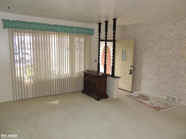 foyer entrance featuring light carpet, visible vents, and wallpapered walls