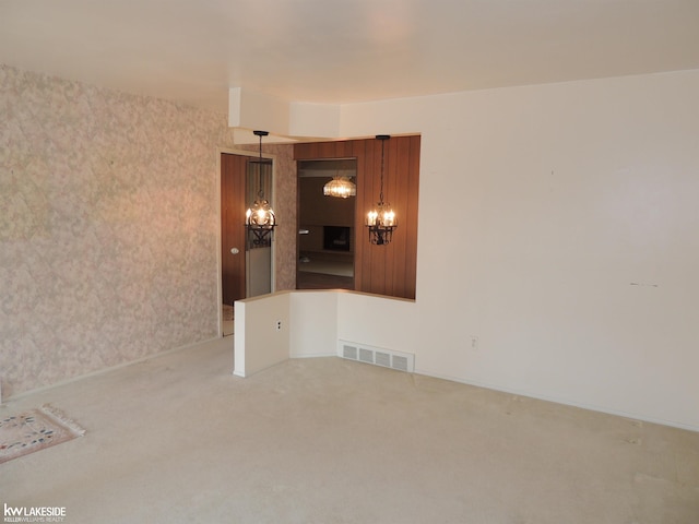 empty room featuring visible vents, an inviting chandelier, carpet flooring, wallpapered walls, and baseboards