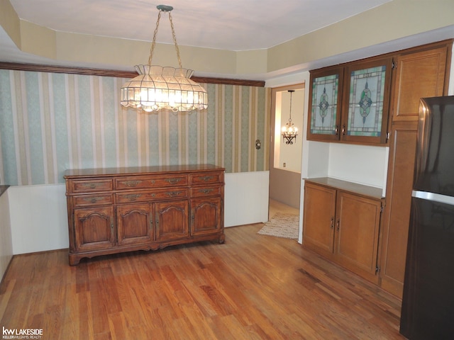 dining space with wallpapered walls and light wood-style floors