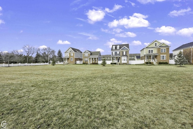 view of property's community featuring a lawn and fence