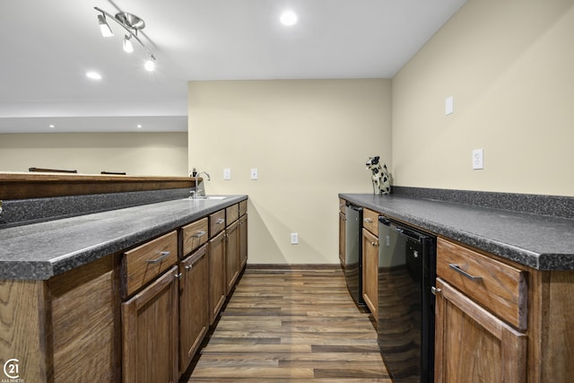 kitchen featuring a sink, dark countertops, a peninsula, dishwasher, and dark wood-style flooring