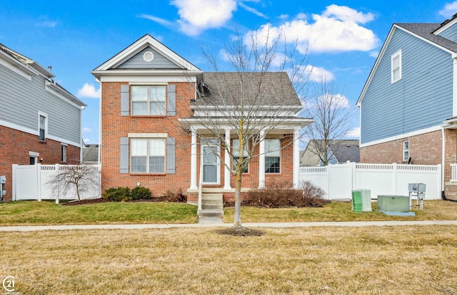 view of front facade with brick siding, a front yard, and fence