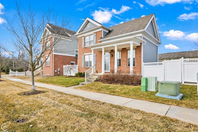 view of front of house with brick siding, a front lawn, and fence