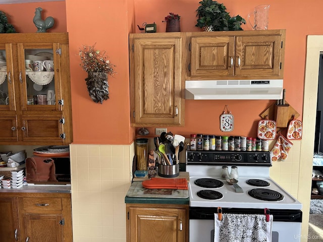 kitchen featuring under cabinet range hood, brown cabinetry, and white range with electric stovetop