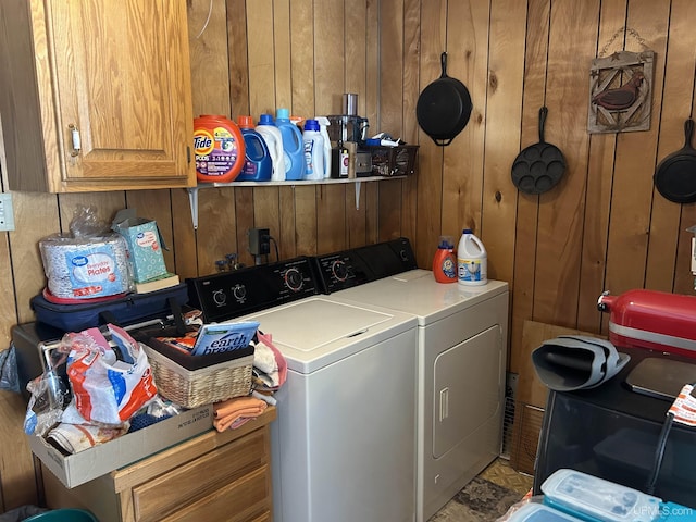 laundry room with cabinet space, washing machine and dryer, and wood walls