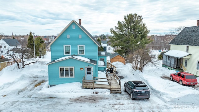 snow covered house featuring a chimney