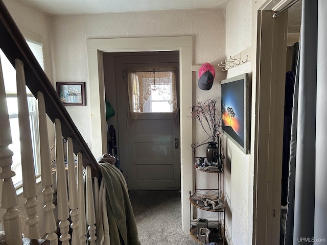 entrance foyer with stairway, carpet flooring, and a textured wall