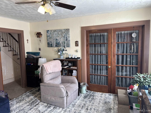 living area featuring stairway, a ceiling fan, carpet floors, and a textured ceiling