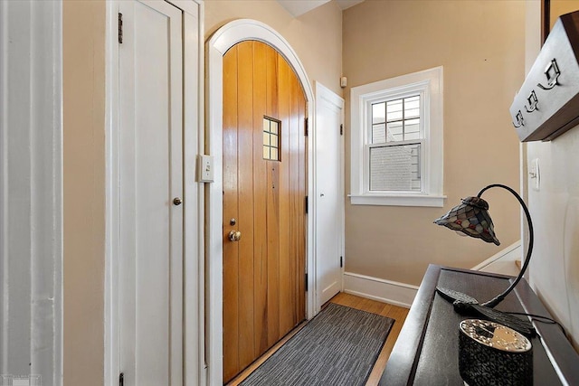 doorway featuring baseboards and wood finished floors