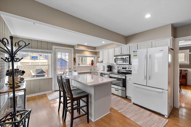 kitchen with light countertops, a healthy amount of sunlight, light wood-type flooring, and stainless steel appliances