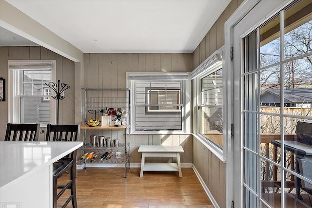 dining room with wood finished floors, baseboards, and wood walls