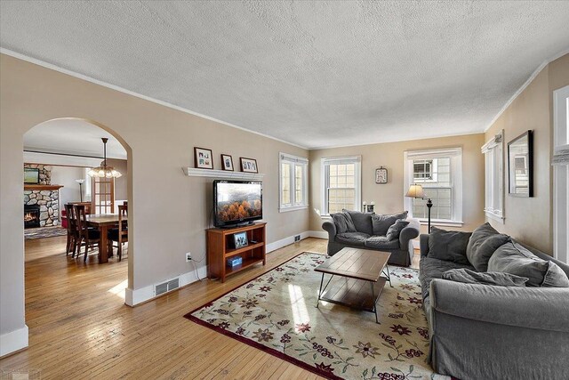 living area featuring visible vents, arched walkways, wood-type flooring, crown molding, and baseboards