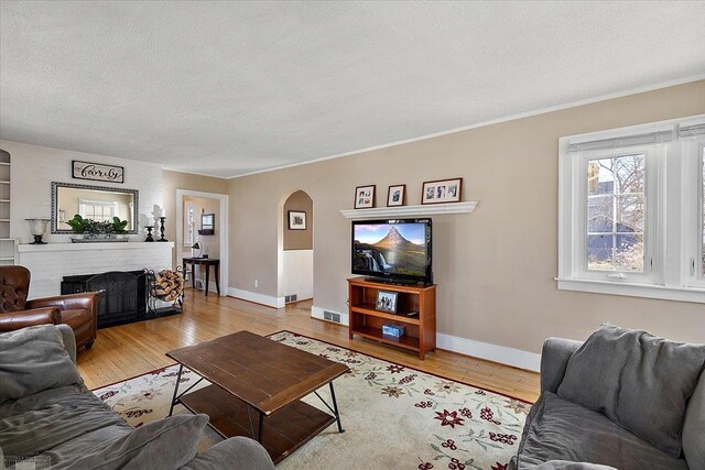 living area with arched walkways, a textured ceiling, and light wood-style flooring