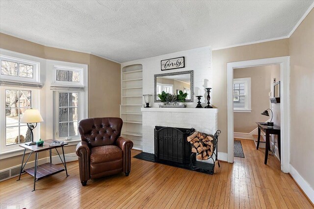 living area featuring hardwood / wood-style floors, a brick fireplace, and plenty of natural light