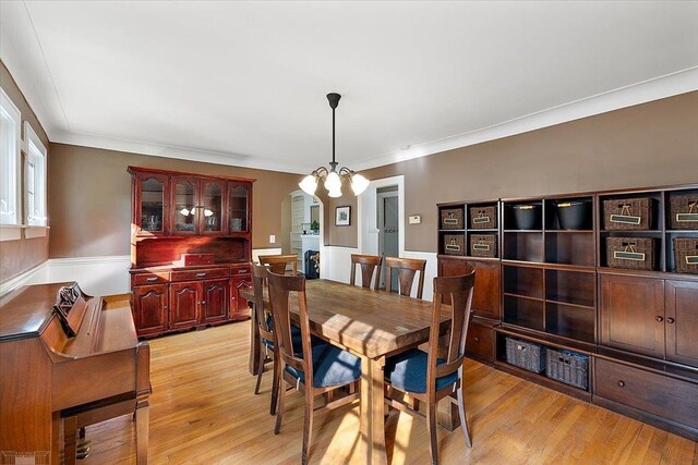 dining space with a notable chandelier, light wood-style floors, and ornamental molding