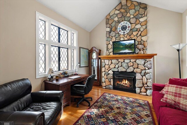 home office featuring vaulted ceiling, a fireplace, and wood finished floors