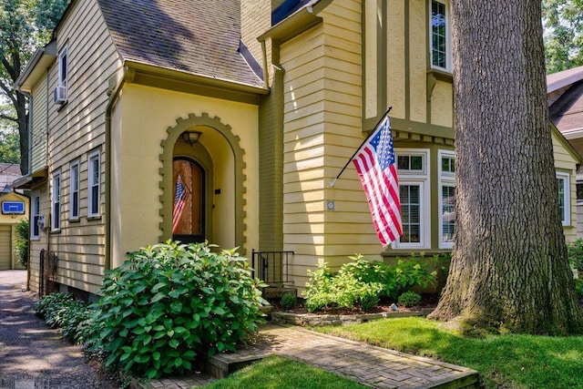 property entrance featuring a garage, roof with shingles, and a chimney