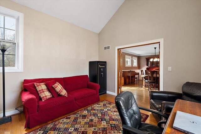 living area featuring visible vents, baseboards, wood finished floors, and a chandelier