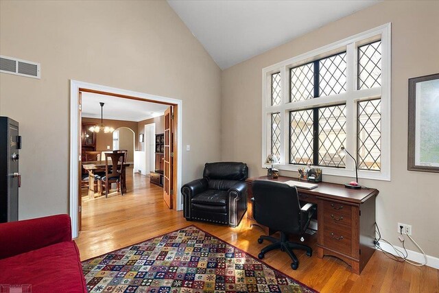 office featuring visible vents, high vaulted ceiling, wood finished floors, arched walkways, and baseboards