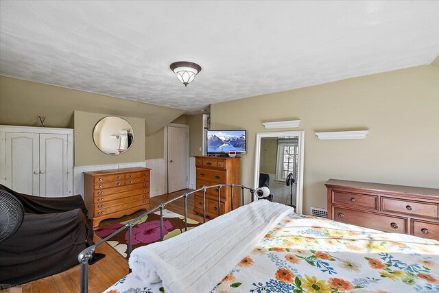 bedroom featuring lofted ceiling, wood finished floors, visible vents, and a closet