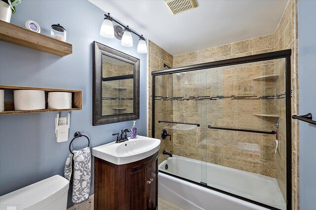 bathroom with enclosed tub / shower combo, visible vents, toilet, and vanity