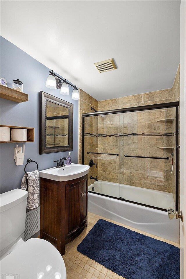 bathroom with vanity, visible vents, shower / bath combination with glass door, tile patterned flooring, and toilet