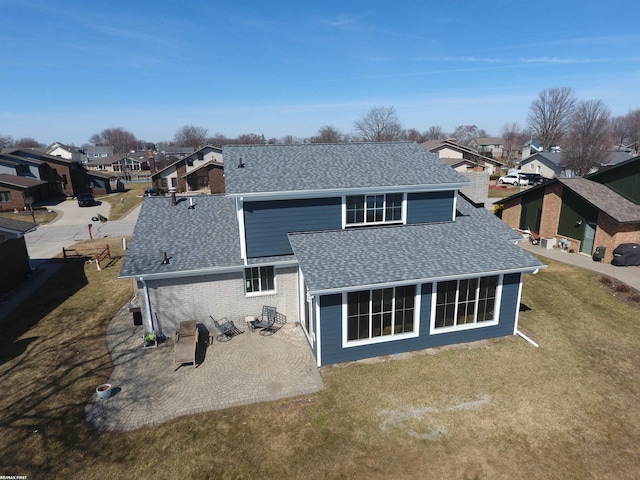 rear view of property with a residential view, a shingled roof, and a yard