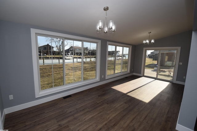 unfurnished dining area featuring dark wood-style floors, baseboards, and a chandelier