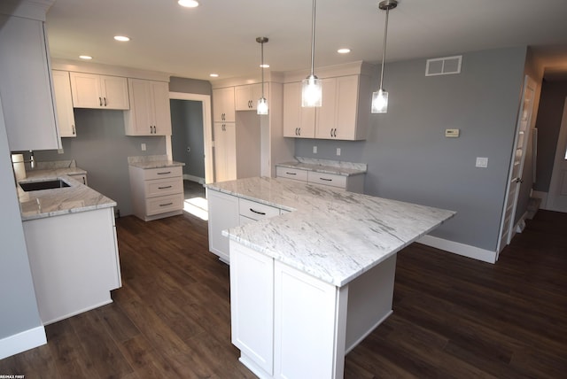 kitchen with visible vents, a kitchen island, dark wood-type flooring, recessed lighting, and a sink