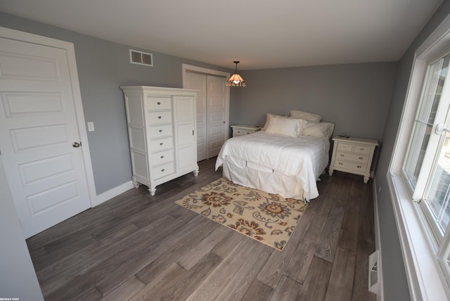 bedroom featuring dark wood-type flooring, baseboards, visible vents, and a closet