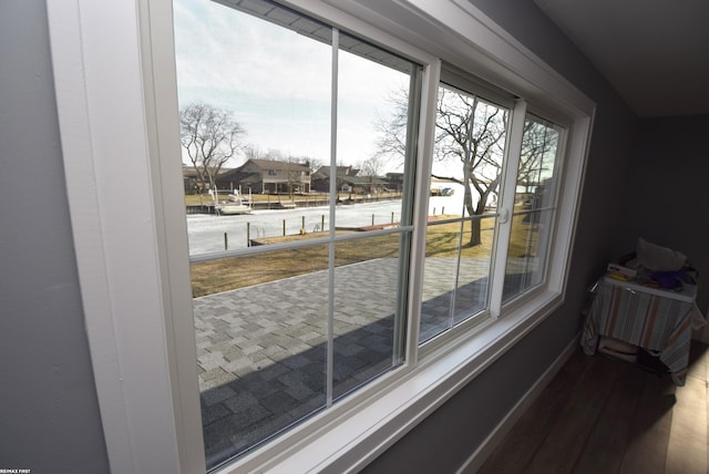 doorway to outside featuring a residential view, wood finished floors, baseboards, and a water view