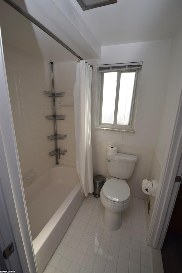 bathroom with tile patterned flooring, toilet, tile walls, and shower / bathtub combination with curtain