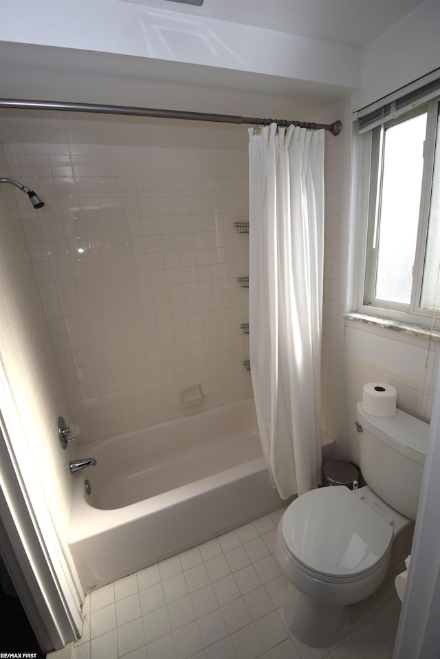 full bathroom with tile patterned floors, shower / bathtub combination with curtain, toilet, and tile walls