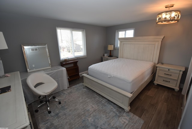 bedroom featuring dark wood-type flooring, a notable chandelier, and multiple windows