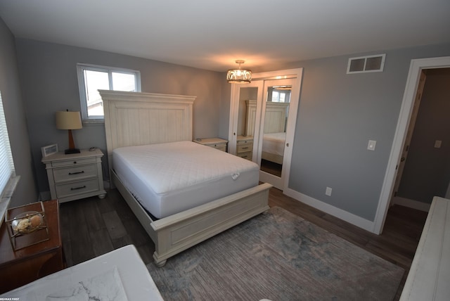 bedroom featuring an inviting chandelier, dark wood-style floors, visible vents, and baseboards