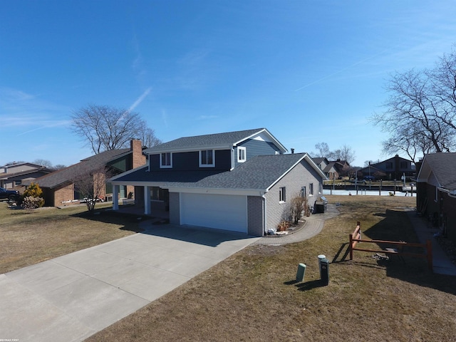 traditional-style home with driveway, a front lawn, an attached garage, a shingled roof, and brick siding