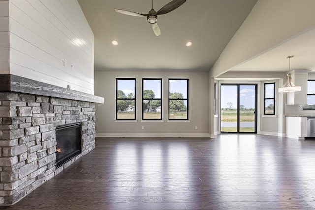 unfurnished living room with high vaulted ceiling, dark wood-type flooring, a stone fireplace, and a ceiling fan